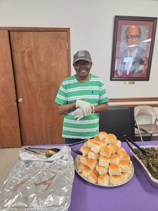 Al Hunter serving rolls at the purple buffet table at the Church BBQ 2026 — MLK Memorial Baptist Church