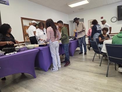 Church family and youth serving themselves at the purple buffet table — MLK Memorial Baptist Church BBQ 2026