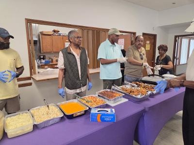 Church members serving food at the BBQ buffet table — MLK Memorial Baptist Church 2026