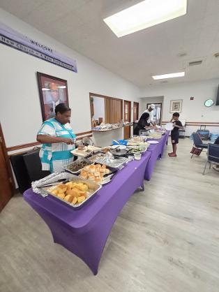 Food buffet line set up on purple tables at the MLK Church BBQ 2026