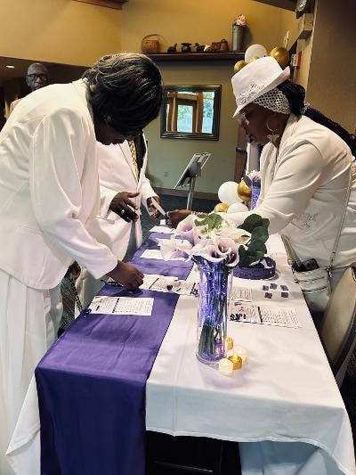 Guests in white attire reviewing programs at the registration table — Golden Jubilee All-White Affair 2026
