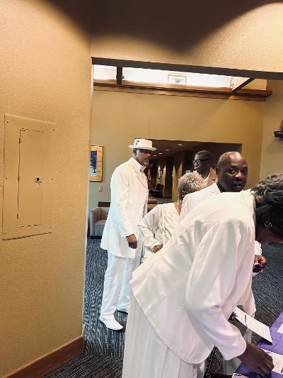 Two guests in white attire at the registration table with calla lily centerpiece and gold balloons — Golden Jubilee All-White Affair 2026