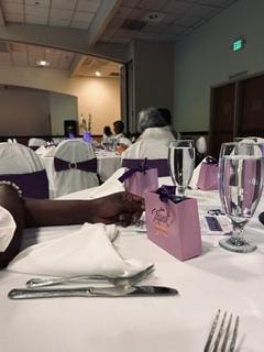 Elegant table setting with white linens, purple sashes, and gift bags at the Golden Jubilee All-White Affair — MLK Memorial Baptist Church 2026