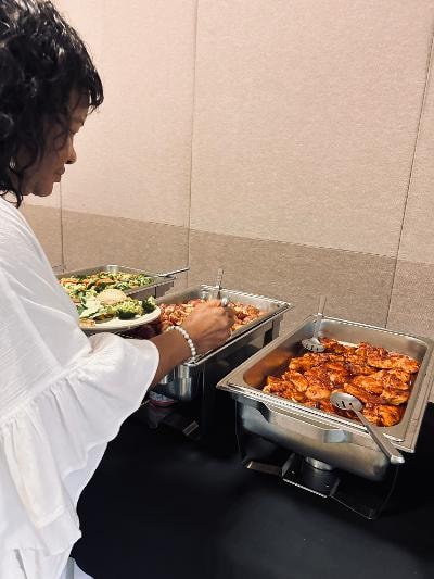 Guest in white dress serving herself from the buffet line at the Golden Jubilee All-White Affair — MLK Memorial Baptist Church 2026