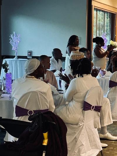 Church members in white attire seated at tables with purple light centerpieces at the Golden Jubilee All-White Affair — MLK Memorial Baptist Church 2026