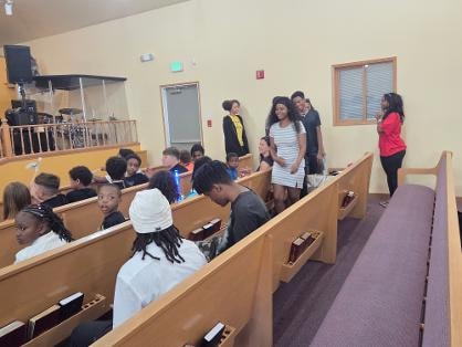 Children seated in church pews during VBS Day 3 Assembly — MLK Memorial Baptist Church