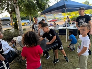 Children and adults gathered outdoors under tent — VBS Day 3 Assembly