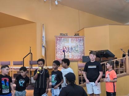 Children on stage speaking at the sanctuary — VBS Day 3 Assembly