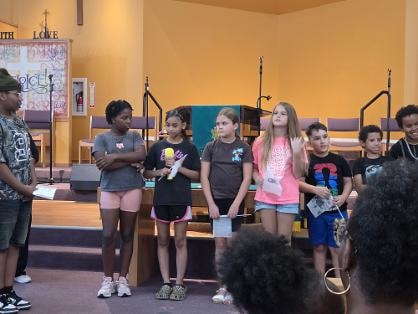 Children presenting on stage at the sanctuary — VBS Day 3 Assembly