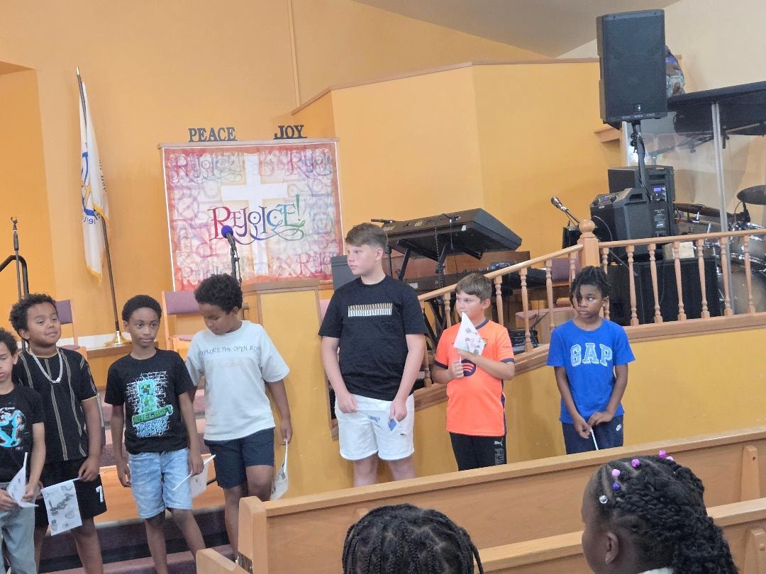 Children standing on stage in the sanctuary during VBS Day 3 Assembly — MLK Memorial Baptist Church