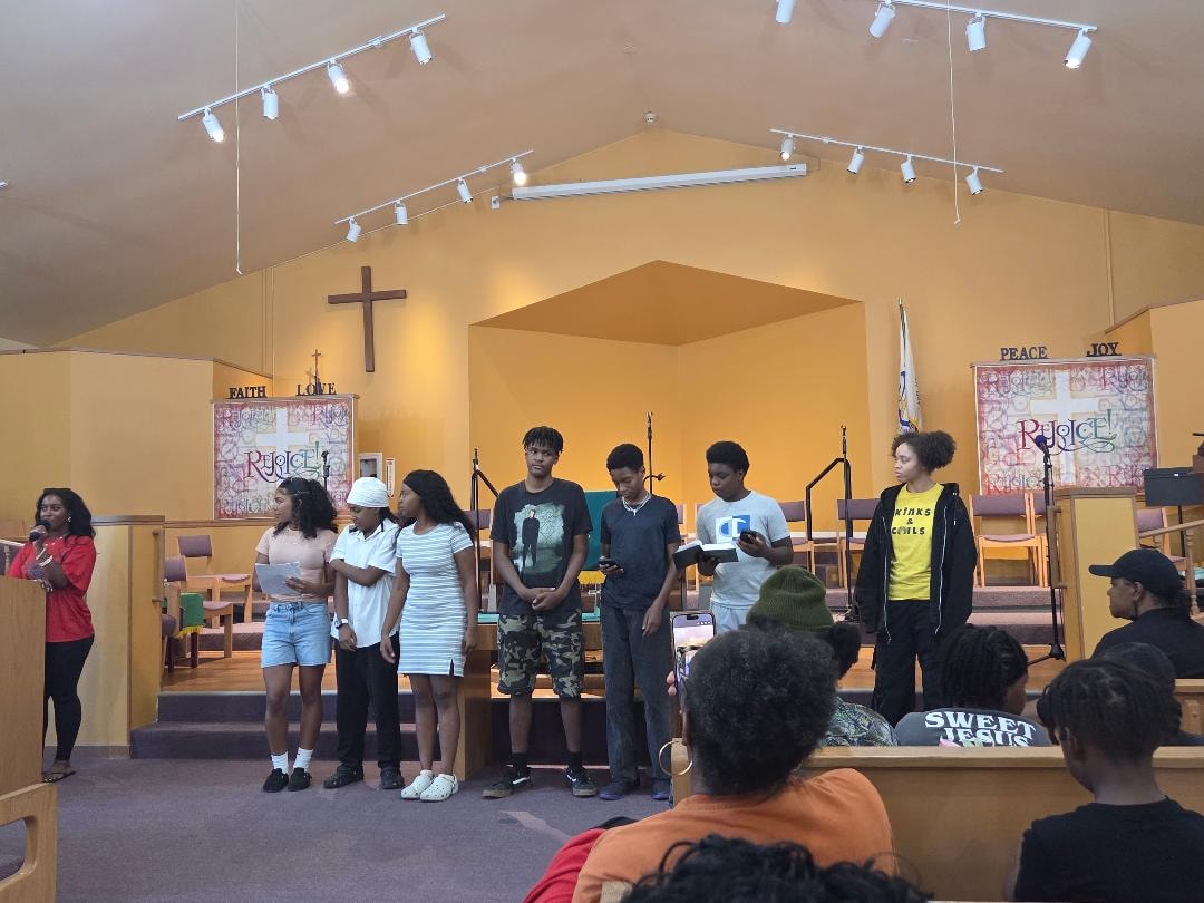 Youth group reading from notes on stage — VBS Day 3 Assembly, MLK Memorial Baptist Church