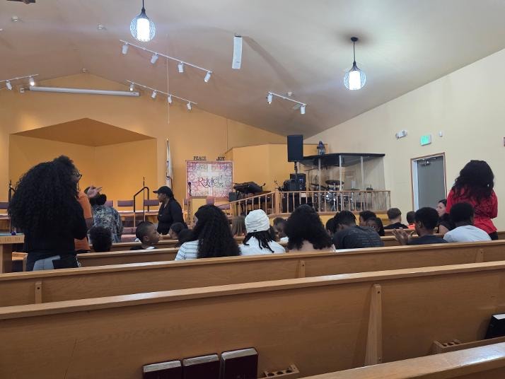 Youth seated in pews facing the stage during VBS Day 3 Assembly — MLK Memorial Baptist Church