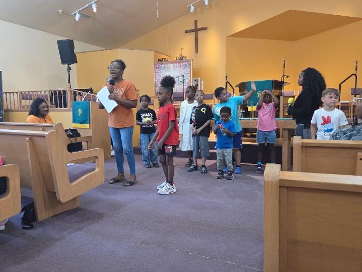 Kim leading children in praise at the sanctuary — VBS Day 3 Assembly