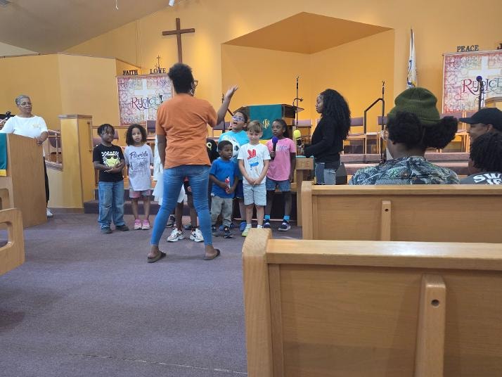 Kim directing children in the sanctuary during VBS Day 3 Assembly — MLK Memorial Baptist Church