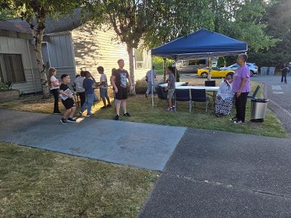 Children and adults gathered outside under blue tent — VBS Day 3 Assembly