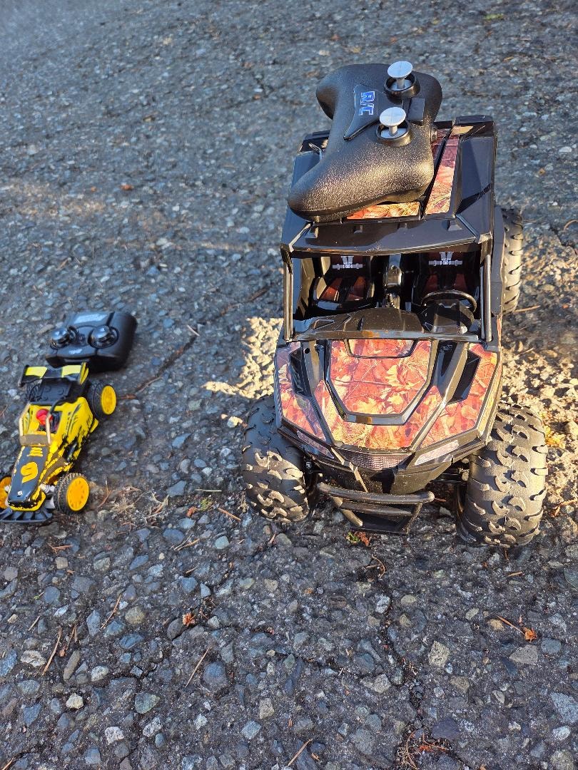 Camo RC truck and yellow RC car on gravel — VBS Day 3 Assembly