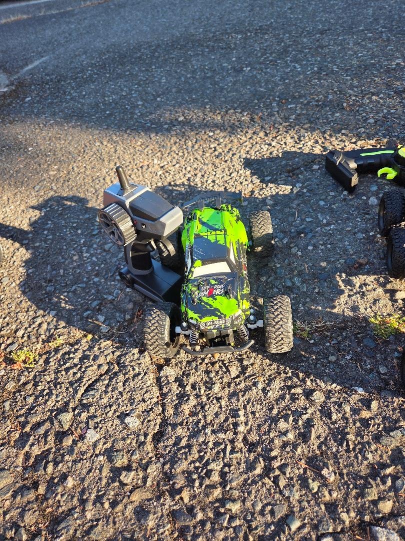 Green RC monster truck with controller on gravel — VBS Day 3 Assembly