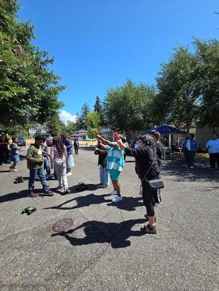 Children and adults gathered outdoors in parking lot — VBS Day 3 Assembly