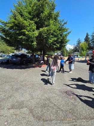 Group gathered in parking lot on sunny day — VBS Day 3 Assembly