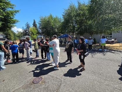 Group gathered in parking lot under sunny skies — VBS Day 3 Assembly