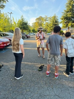 Children watching RC car demonstration in parking lot — VBS Day 3 Assembly