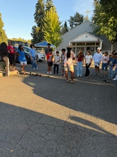 Large group of children and adults gathered in parking lot for RC cars — VBS Day 3 Assembly